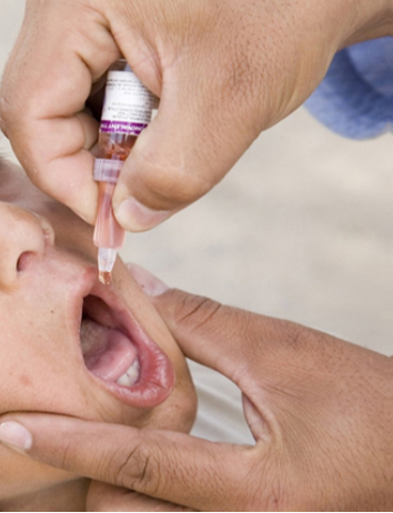 A photograph shows a child being given an oral vaccine.