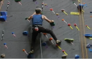 A picture shows a person in a harness ascending a climbing wall.