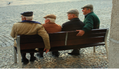 Four people are sitting on a bench looking off in the same direction.