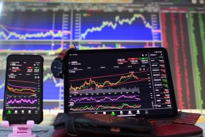 multiple computer devices showing complicated charts of stock market data