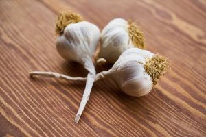 Three garlic on a wooden surface