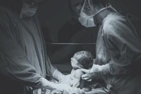 A newborn being delivered via C-section