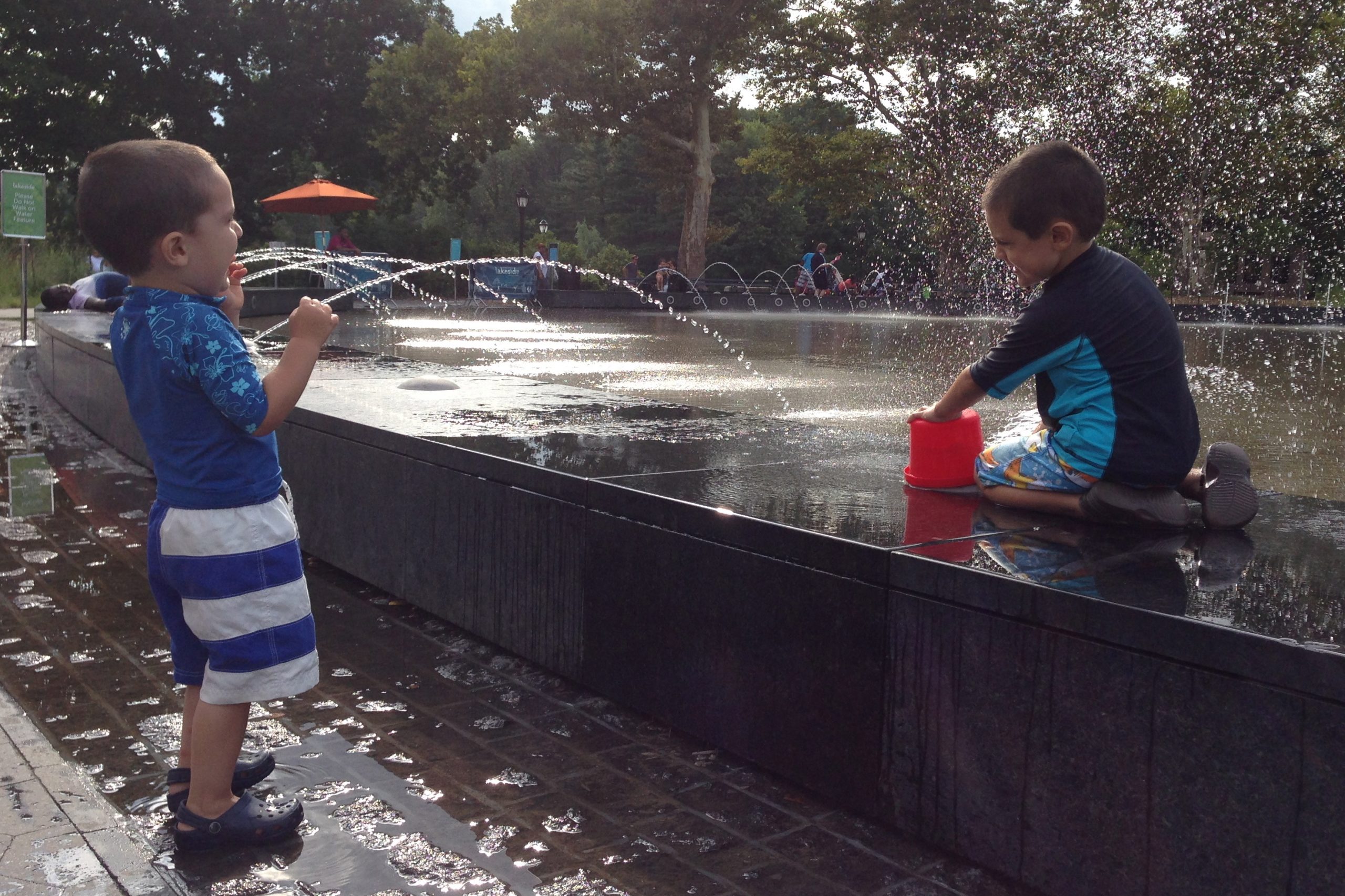 two young children playing and laughing at a splash pad