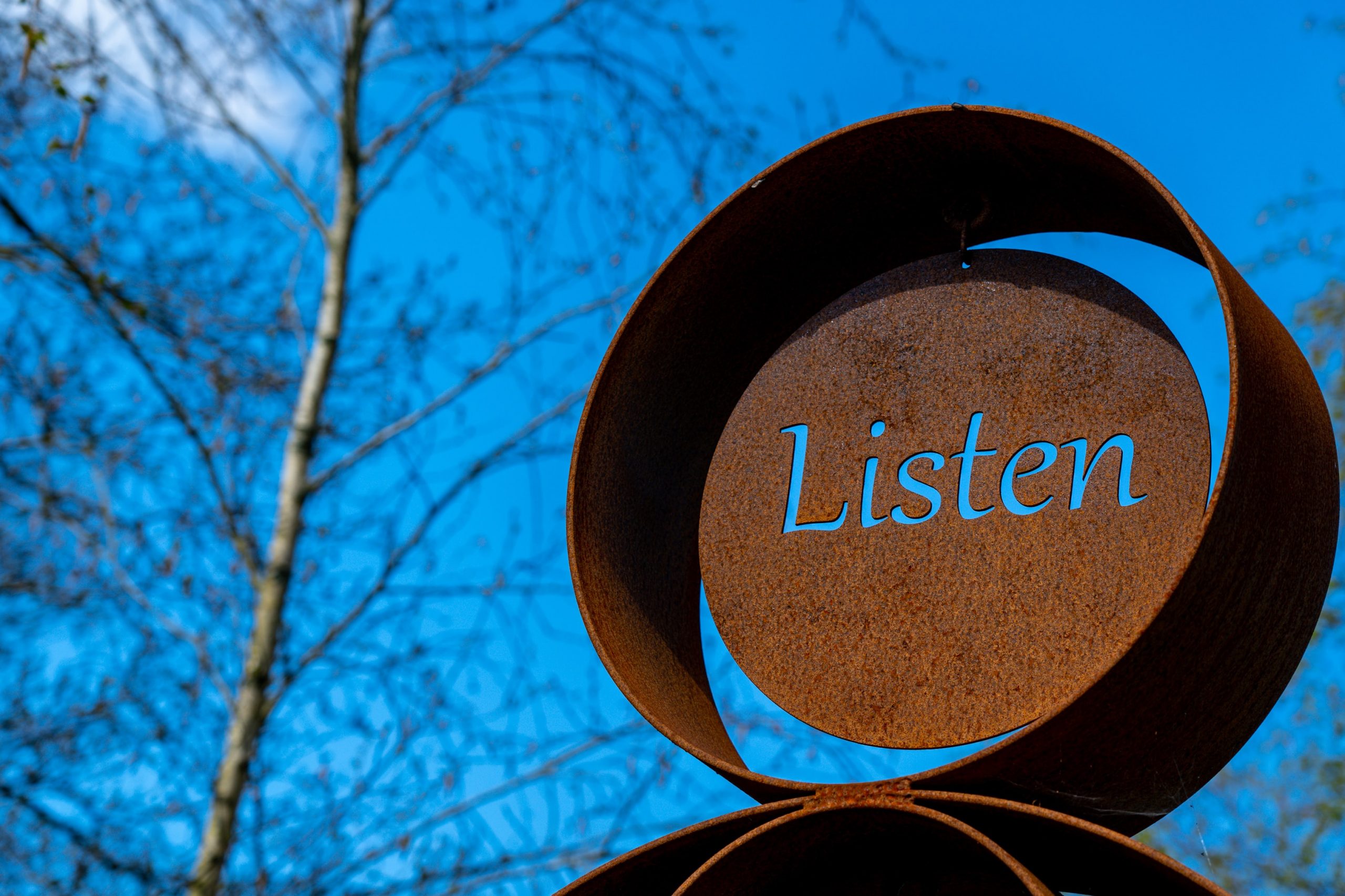 an outdoor sign showing the word listen