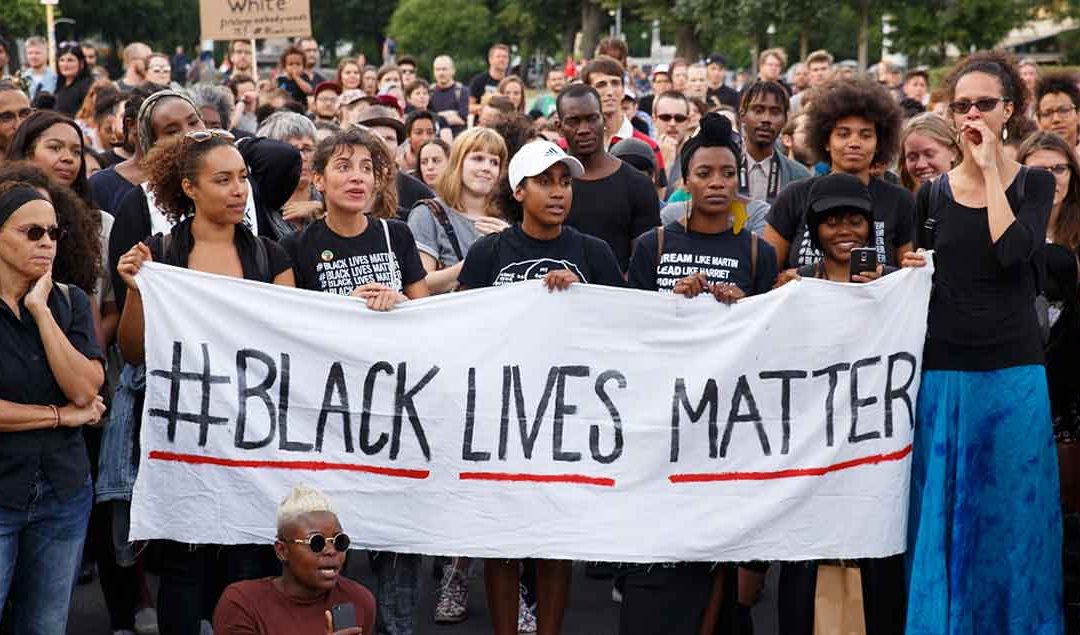 Photo of protestors holding a banner that says #Black Lives Matter
