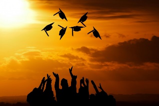 Sunset scene with graduates in silhouette tossing their caps in the air