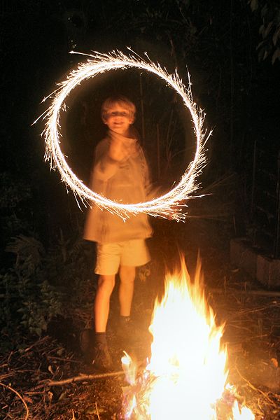 Child swirling a sparkler to form the shape of a circle