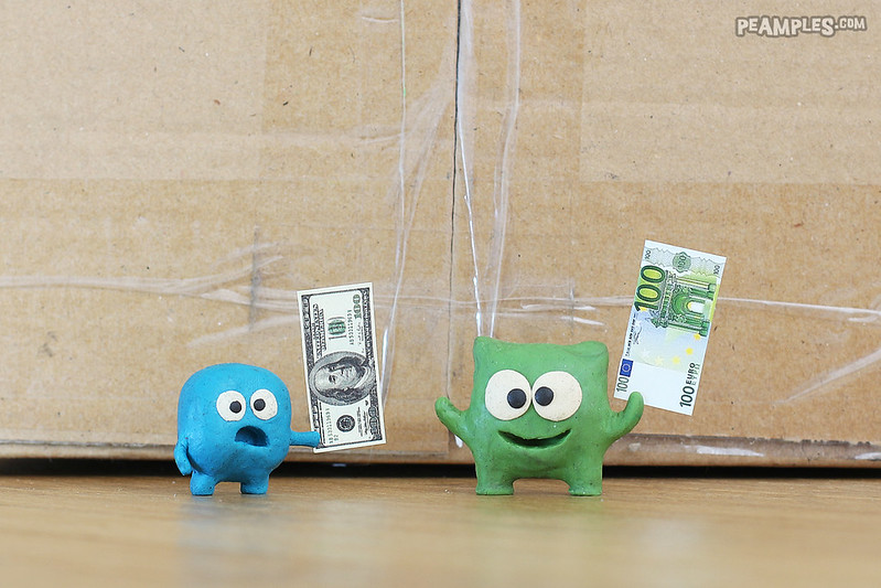 two critters holding up different currencies