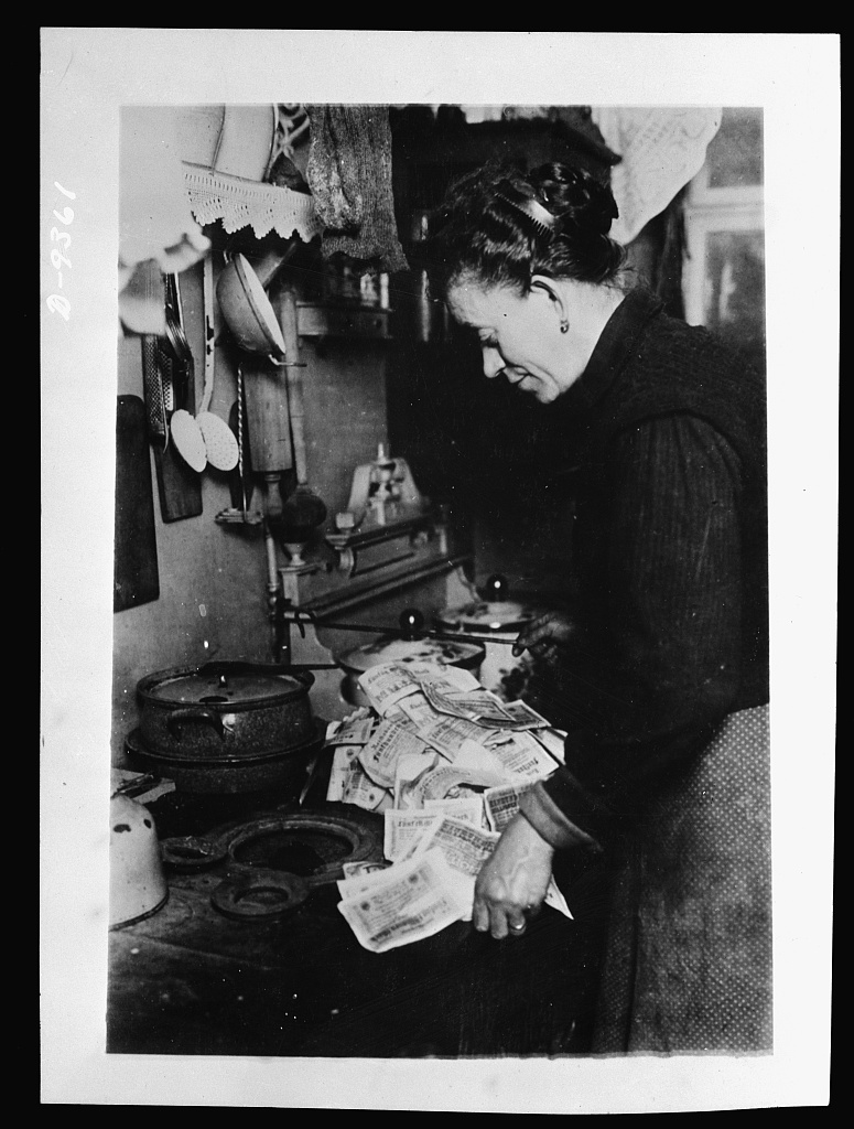 money is so worthless in Germany's hyperinflation that woman lights the stove with cash
