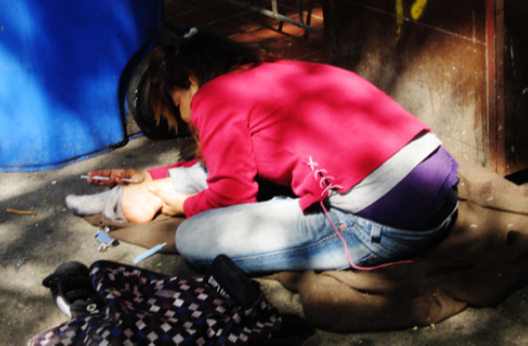 A photograph shows a person injecting heroin intravenously with a hypodermic needle into her ankle.