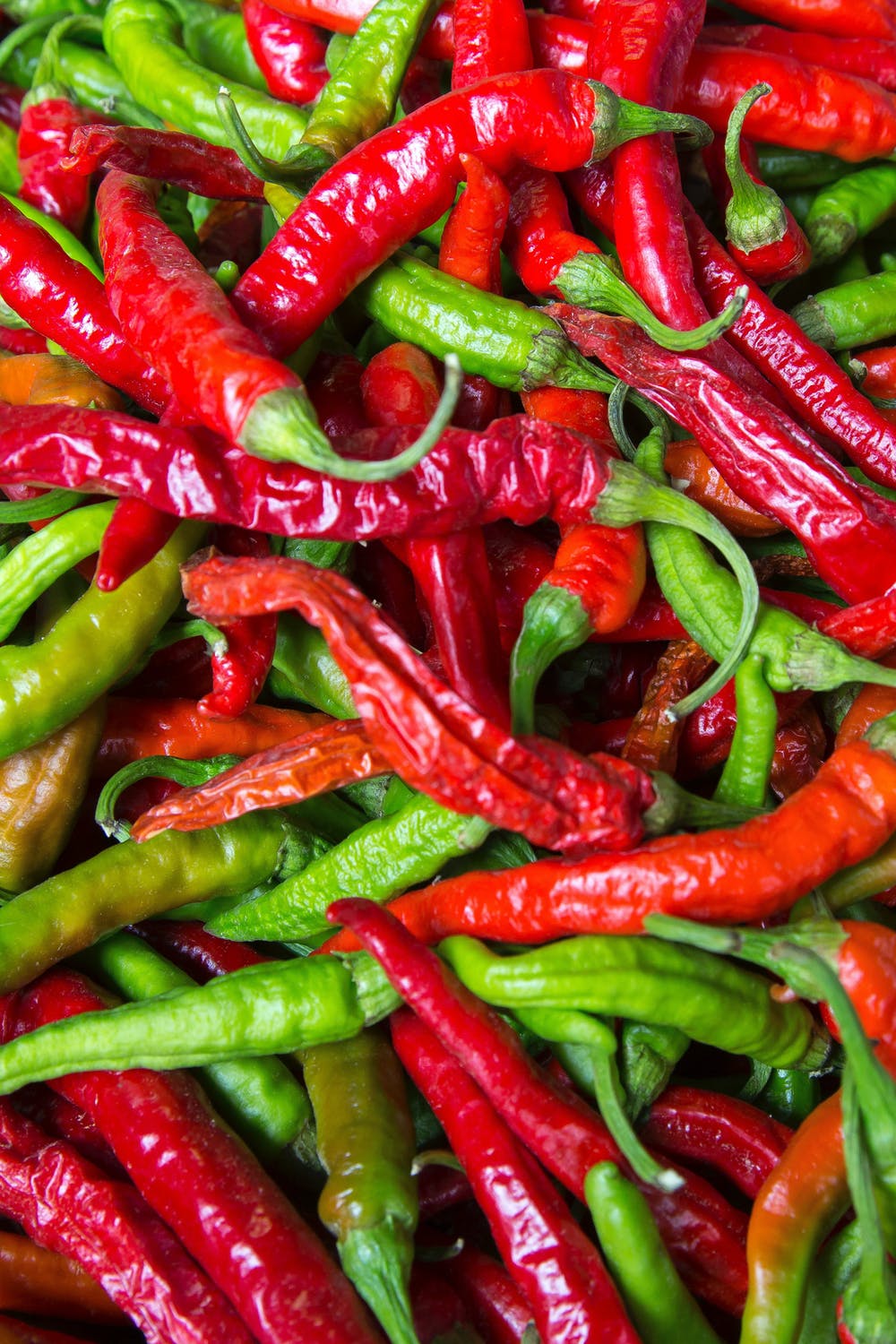 Red and Green Chili peppers are sitting in a pile